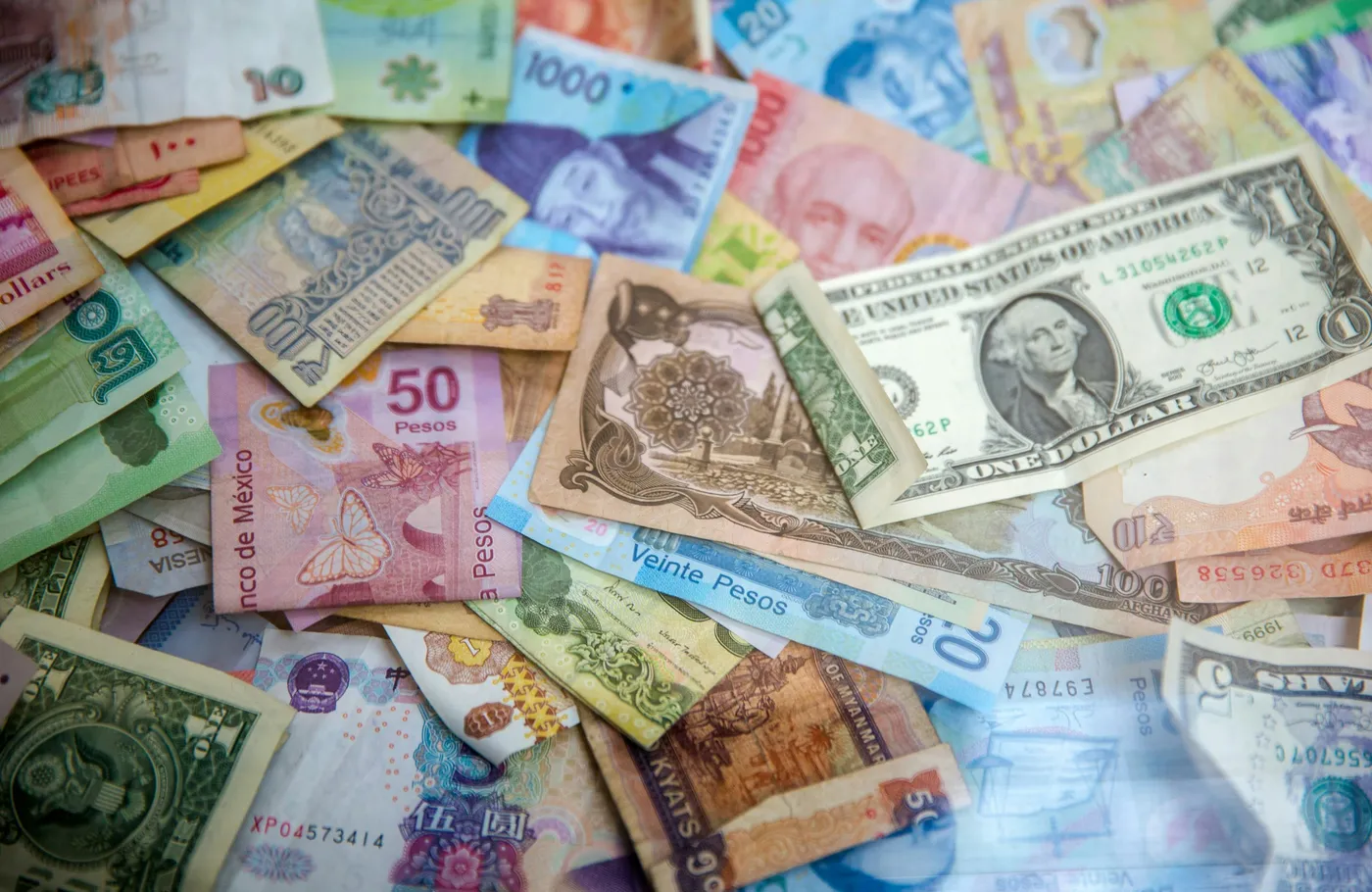Banknotes from many countries spread out together, including US dollars and Mexican pesos