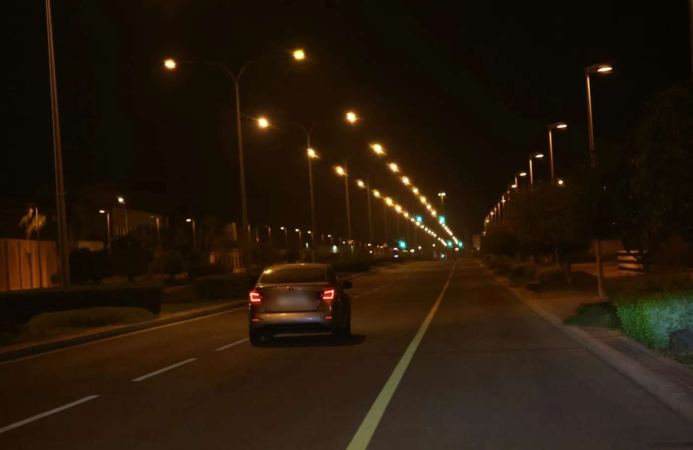 A car driving along a lit road at night in Mesaieed, Qatar